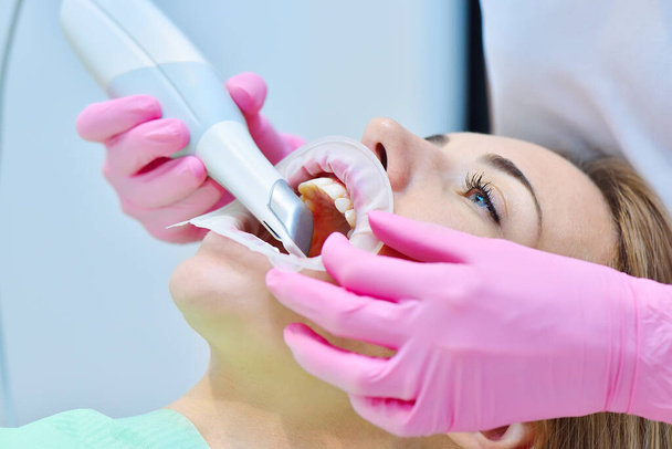 Woman dentist using dental intraoral scanner while examining patient teeth in dental clinic. Intraoral scanning with scanning machine concept. Close up - Fotó, kép