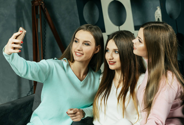 Cheerful girlfriends have fun and take selfies on mobile, at home. - Fotoğraf, Görsel