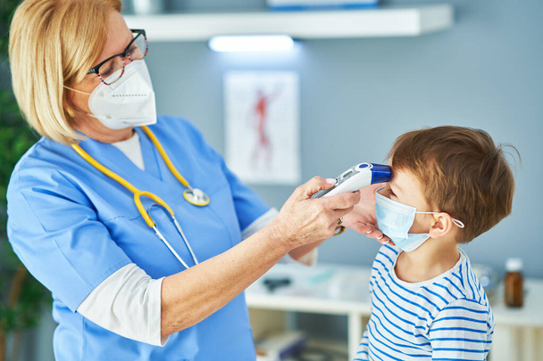 Pediatrician doctor examining little kids in clinic temperature check - Foto, immagini