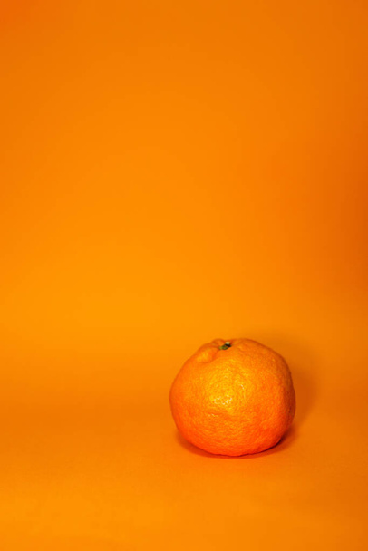 На поверхні оранжевого фону свіжий апельсин. Концептуальна фотографія молодого і старого віку, внутрішня краса, самотність, брехня, хвороби. Доріан Грей - Фото, зображення
