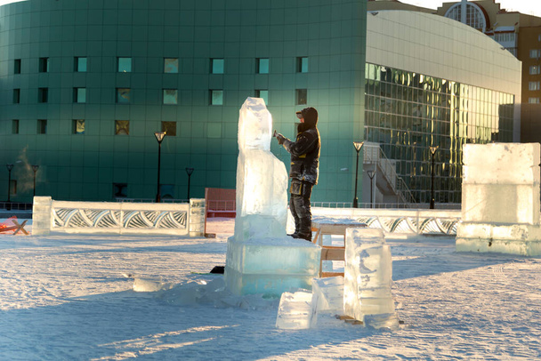 El escultor corta los contornos de hielo de hielo con una motosierra para Navidad
 - Foto, Imagen