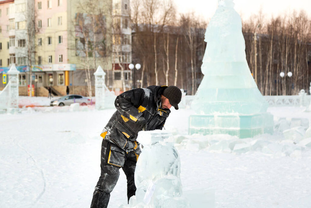 El escultor corta los contornos de hielo de hielo con una motosierra para Navidad
 - Foto, imagen