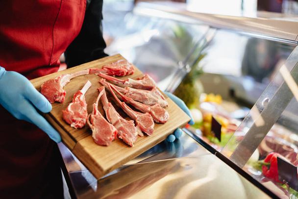 Close up of a butcher setting raw lamb ribs in a butcher shop - Foto, afbeelding