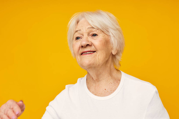 elderly woman in casual t-shirt gestures with his hands isolated background - Foto, Imagem