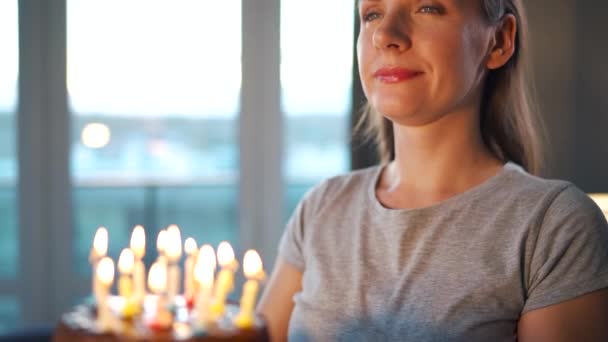 Feliz mujer emocionada haciendo deseos preciados y soplando velas en el pastel de vacaciones, celebrando el cumpleaños en casa - Metraje, vídeo