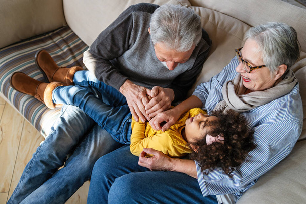 Portrait of happy grandparents with child playing together at home. Family love togetherness concept - Photo, image