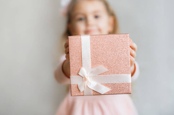 niña linda da una caja de regalo rosa, tiene un regalo en sus brazos. Enfoque selectivo. Copiar espacio. Concepto de cumpleaños, concepto de día de la madre - Foto, Imagen