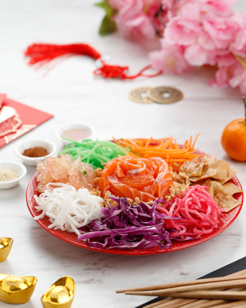 Pyszne i kolorowe Wyświetlanie chińskiej kuchni dobrobytu, Yee Sang lub dobrobytu rzut. Paski marchwi, kapusta fioletowa, surowy łosoś, orzeszki ziemne, placki, Pomelo - Zdjęcie, obraz