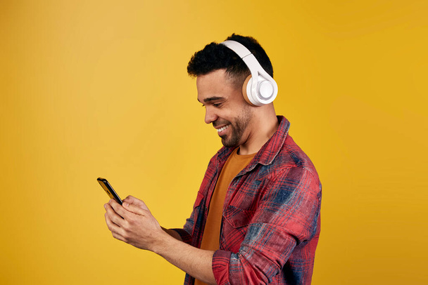 Вміст етнічного чоловіка в навушниках, що переглядають смартфон
 - Фото, зображення