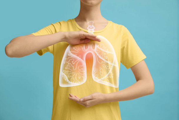 Woman holding hands near chest with illustration of lungs on turquoise background, closeup - Фото, зображення