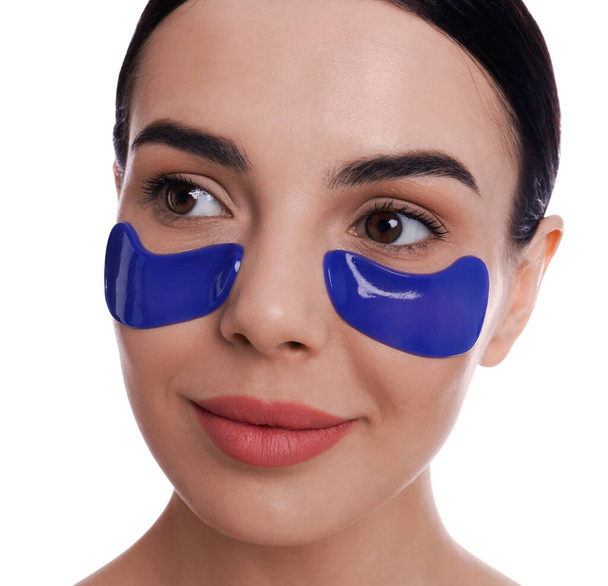 Beautiful young woman with under eye patches on white background - Foto, Imagem