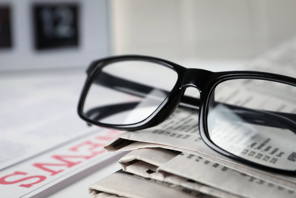 Glasses on stack of newspapers, closeup view - Foto, Bild