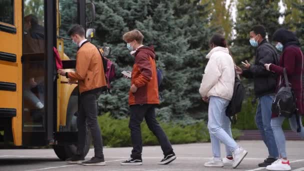 Ocupado en los teléfonos estudiantes adolescentes subiendo al autobús escolar - Metraje, vídeo