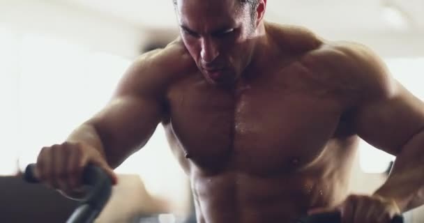 Putting those muscles to work. 4k video of a muscular young man working out on an exercise bike in the gym. - Filmagem, Vídeo