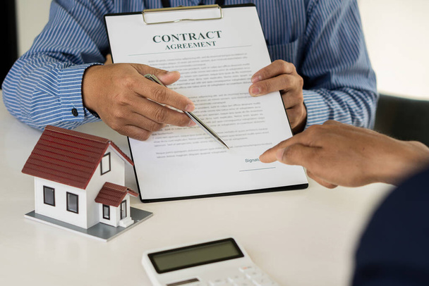 営業担当者は、住宅購入契約の条件について説明し、顧客に住宅販売と住宅保険を合法的に契約するための文書に署名するように依頼します。不動産ビジネスのアイデア - 写真・画像
