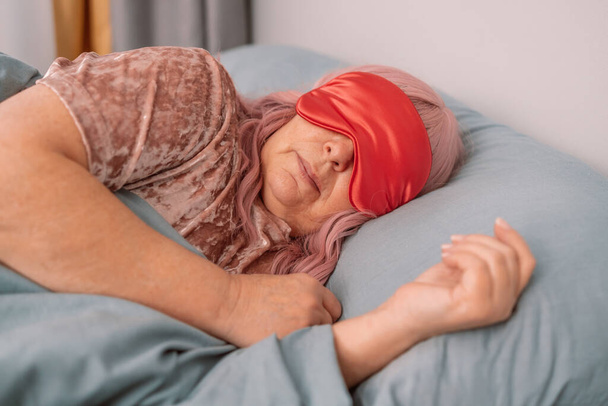 Сладкие сны. Красивая женщина 50-х годов в маске для глаз спит в постели рано утром. Люди, расслабиться и комфорт - Фото, изображение