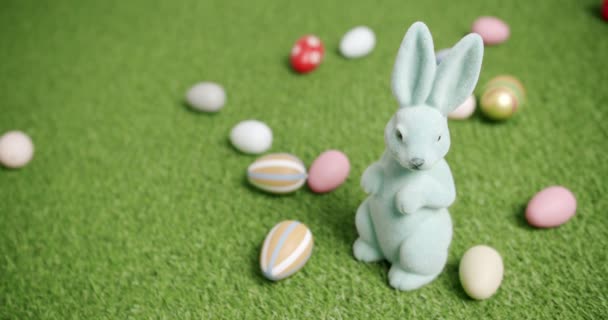 Rabbit toy on a background of green grass with many colored eggs, text messages - Footage, Video