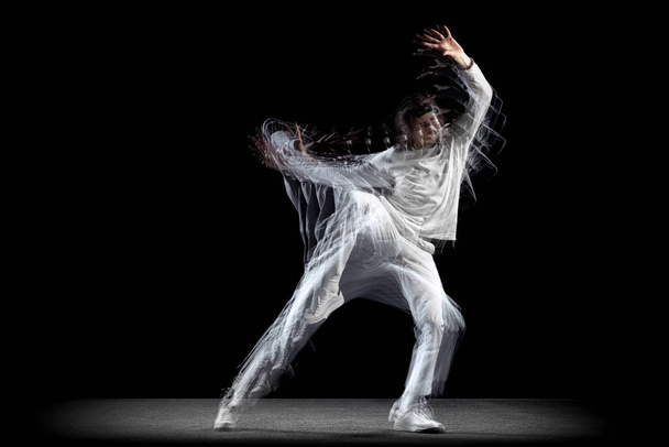Young man, hip-hop dancer in action, motion isolated on dark background with sroboscope effect. Youth culture, hip-hop, movement, style and fashion, action. - Φωτογραφία, εικόνα