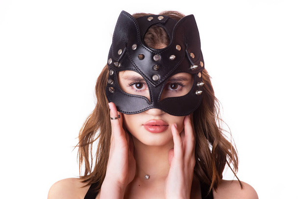 Kůže, elegantní, černá maska kočky na mladém samičím modelu na bílém pozadí. izolovat. detailní záběr, portrét. Černý kožený oděv. Stylové opasky pod šaty. Kožený postroj - Fotografie, Obrázek