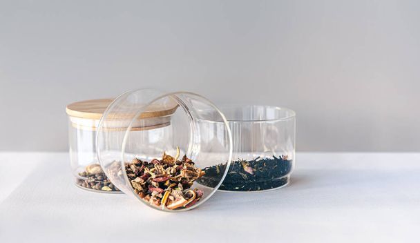 Différents types de thé dans des bocaux en verre sur un fond clair, isolé. - Photo, image