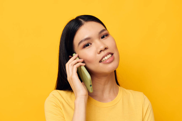 pretty brunette phone communication fun use yellow background unaltered - Fotografie, Obrázek