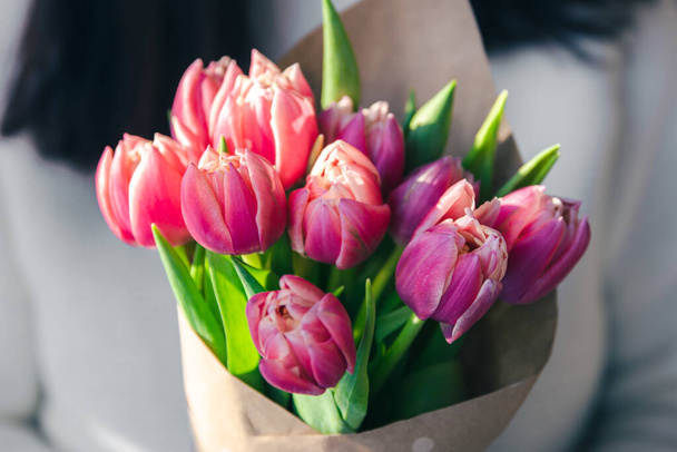 Close-up, bukiet różowych tulipanów w rękach kobiet. - Zdjęcie, obraz
