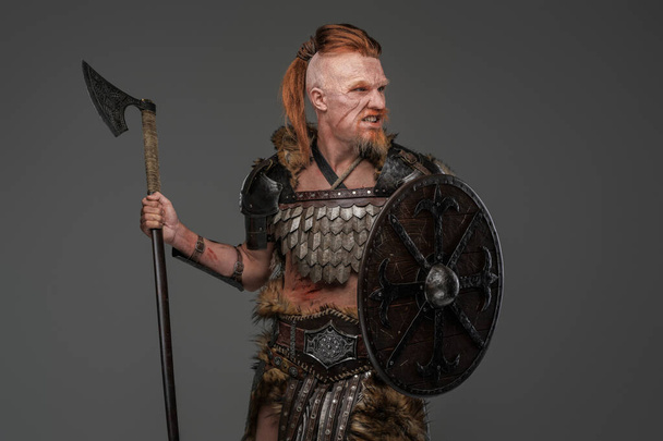 Barbaric viking warrior wielding axe and shield isolated on gray - Photo, Image