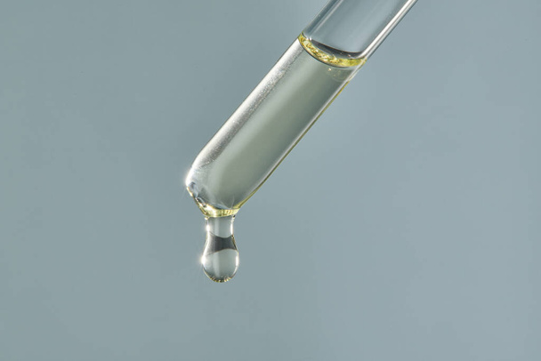A drop of cosmetic aromatic oil drips from the pipette. - 写真・画像