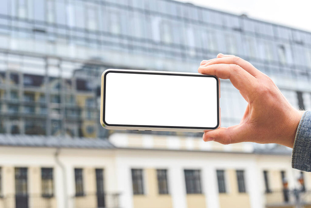 Close-up, Mockup of a smartphone in the hands of a man. Against the backdrop of a glass business center - Foto, Bild