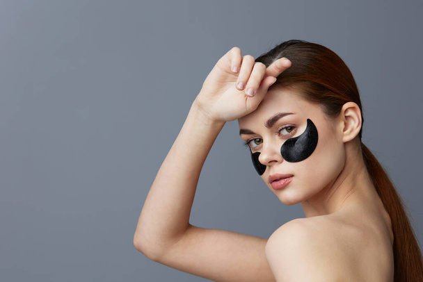 jeune femme avec des patchs sur le visage propre peau santé rajeunissement fond gris - Photo, image