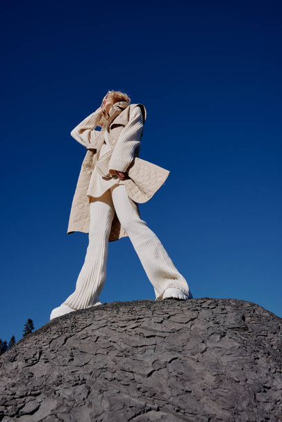молода жінка в осінньому одязі стоїть на скелястому ландшафті блакитного неба
 - Фото, зображення