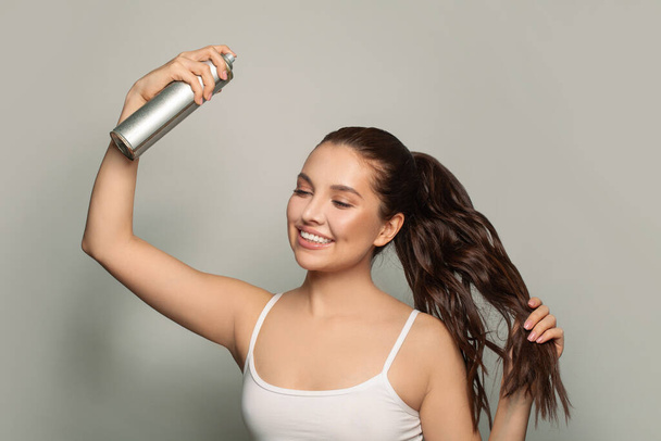 Mulher bonita aplicando spray de cabelo em seu cabelo. - Foto, Imagem