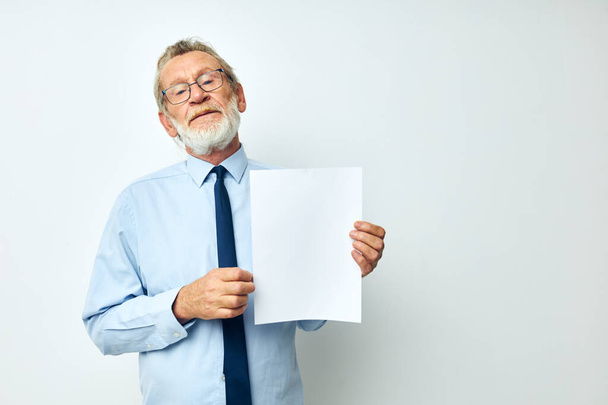 Senior grey-haired man in a shirt with a tie copy-space sheet of paper isolated background - Foto, Imagen