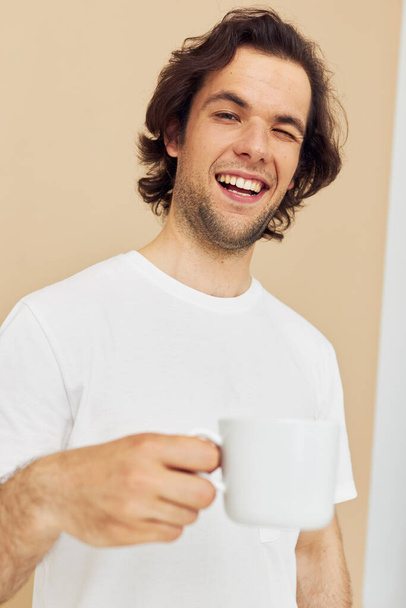 handsome man with a white mug in his hands emotions posing isolated background - Фото, зображення