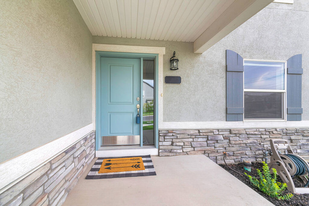Lichtblauwe voordeur met kluisje en deurmat op een betonnen entree - Foto, afbeelding
