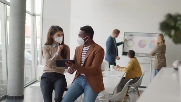 Група молодих багатонаціональних бізнесменів, які працюють разом з масками захисту обличчя та готують новий проект на зустрічі в офісі
 - Кадри, відео
