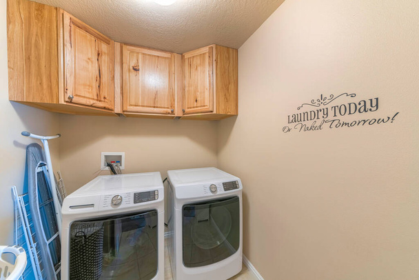 Mała pralnia z napisami na beżowej ścianie - Zdjęcie, obraz