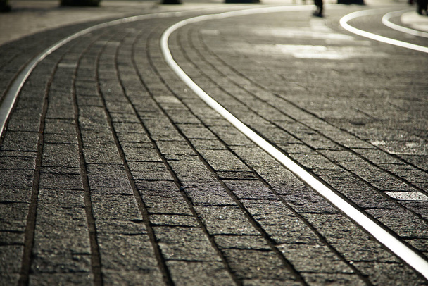 Cobblestone kadut ja raitiovaunun kiskot valaistu laskevan auringon                                - Valokuva, kuva