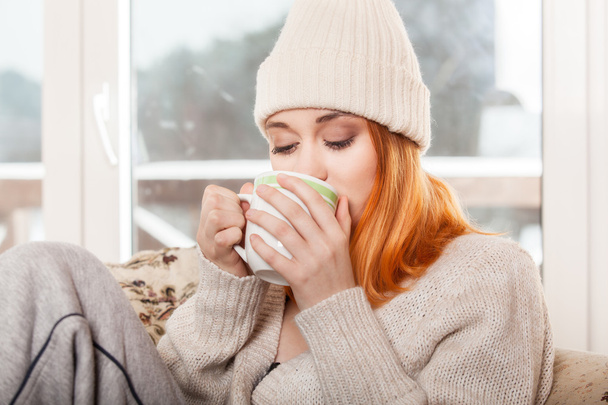 Woman wearing warm clothing and drinking hot drink - Fotoğraf, Görsel