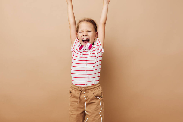 Portrait of happy smiling child girl in striped t-shirt headphones gesture hands childhood unaltered - 写真・画像
