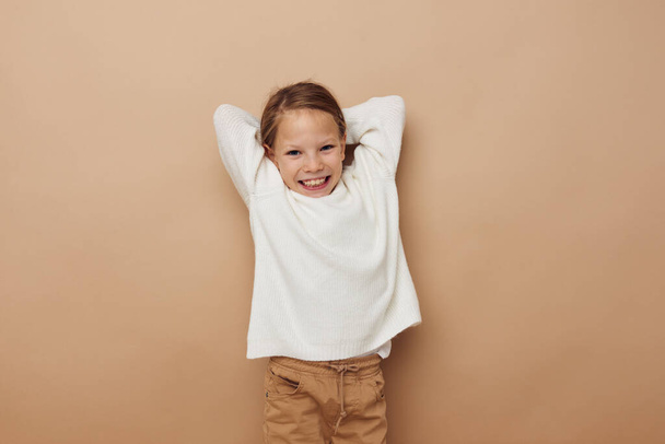 little girl in white sweater posing hand gestures beige background - Fotó, kép