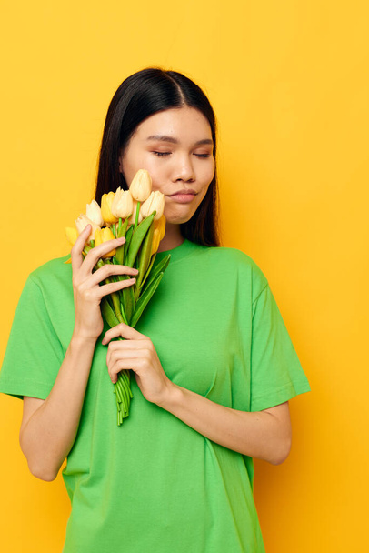 Portrait Asian beautiful young woman bouquet of flowers romance spring posing yellow background unaltered - Valokuva, kuva