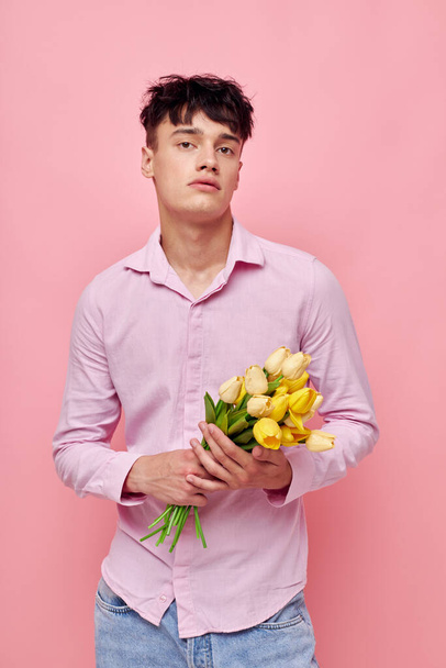portrait of a young man Bouquet of yellow flowers romance posing fashion model studio - Foto, afbeelding