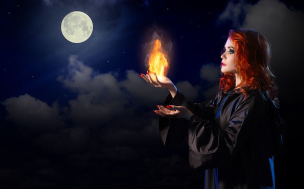Witch with flame on night sky background - Φωτογραφία, εικόνα