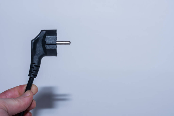 plug held in one hand save electricity left view with gray background - Photo, Image