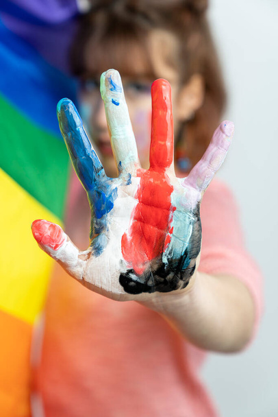 Happy woman showing hands painted in colorful paints on white background. LGBT pride. Happy woman with lgbt flag   - Foto, imagen