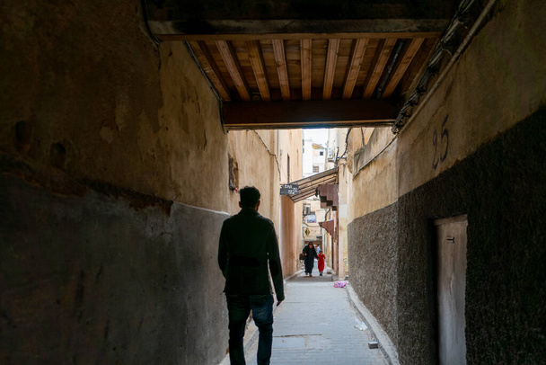 Man walks through a narrow street in the old medina of Fes - Фото, зображення