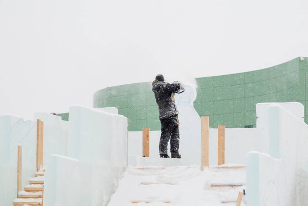Скульптор вырезает контуры будущей композиции бензопилой в ледяной плите - Фото, изображение