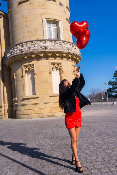 Brunette caucasian girl in love with heart balloons on Valentine's day, walking with them on the day of celebration - Photo, image