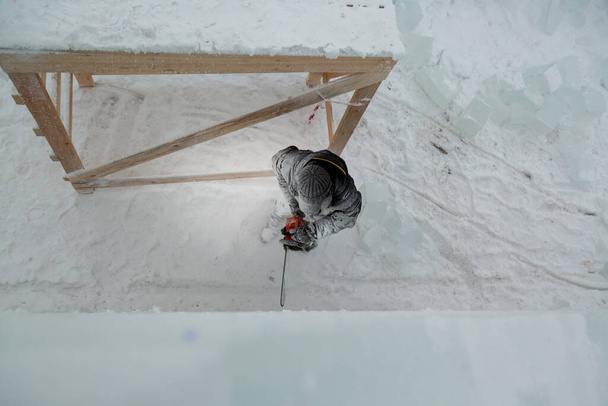 Heykeltıraş, gelecekteki kompozisyonun hatlarını bir buz tabakasında testere ile keser. - Fotoğraf, Görsel